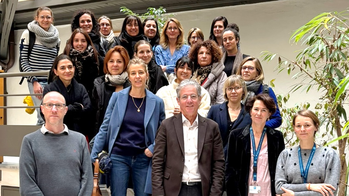 Intérieur. Groupe de 22 personnes sur 4 rangées. 2 personnes sur la droite portent un tour de cou avec le logo bleu des HCL. 