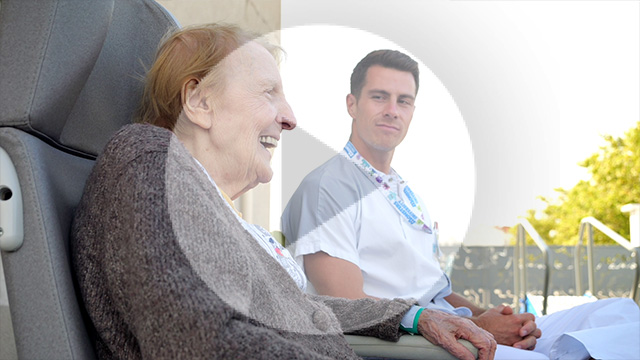 Patiente qui sourit et soignant en arrière plan qui la regarde