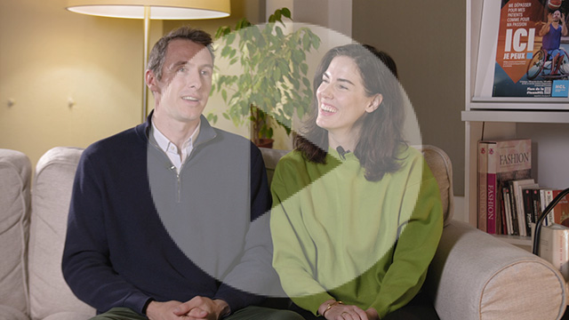 Benoit en noir et Natalia en pull vert souriante sont assis sur un canapé