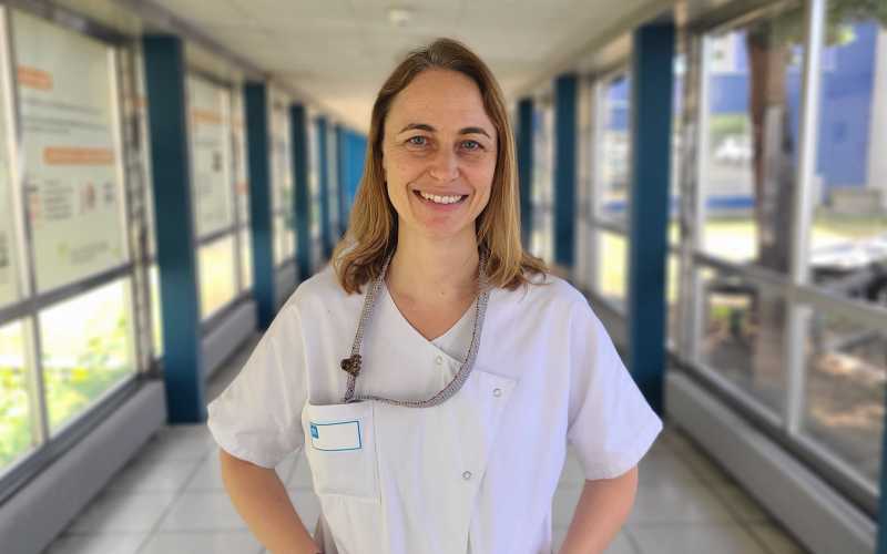 Jeune femme souriante dans un couloir d'hôpital en blouse blanche
