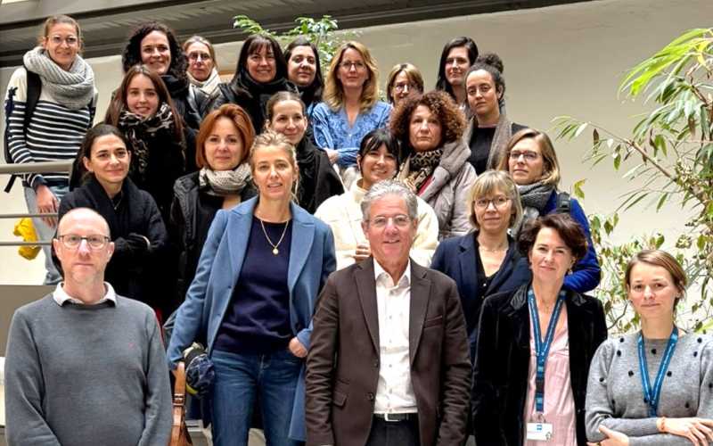 Intérieur. Groupe de 22 personnes sur 4 rangées. 2 personnes sur la droite portent un tour de cou avec le logo bleu des HCL. 