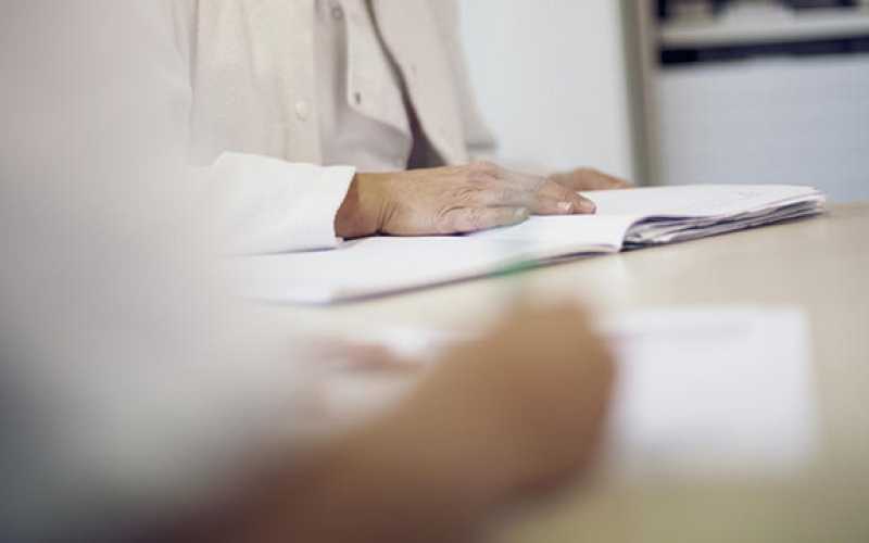 Main qui tient un stylo et main sur cahier de note