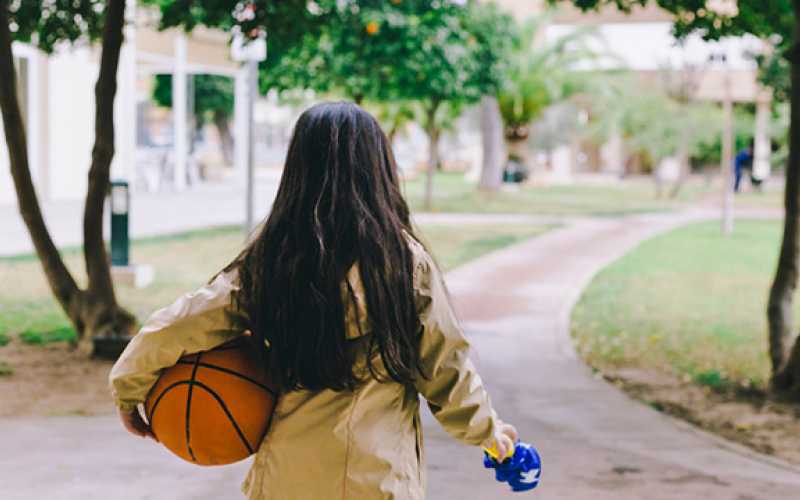 Adolescente de dos avec un ballon de basket à la main
