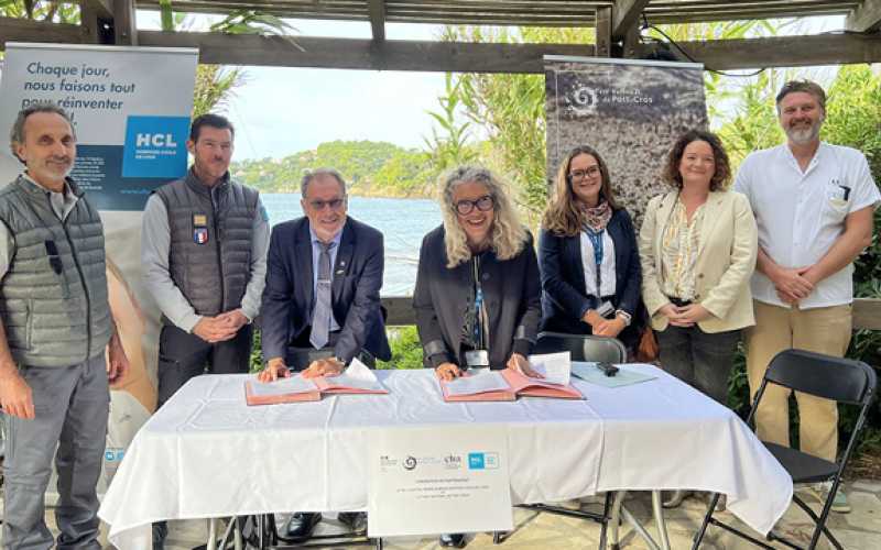 7 personnes dont 2 en train de signer des documents sur une table