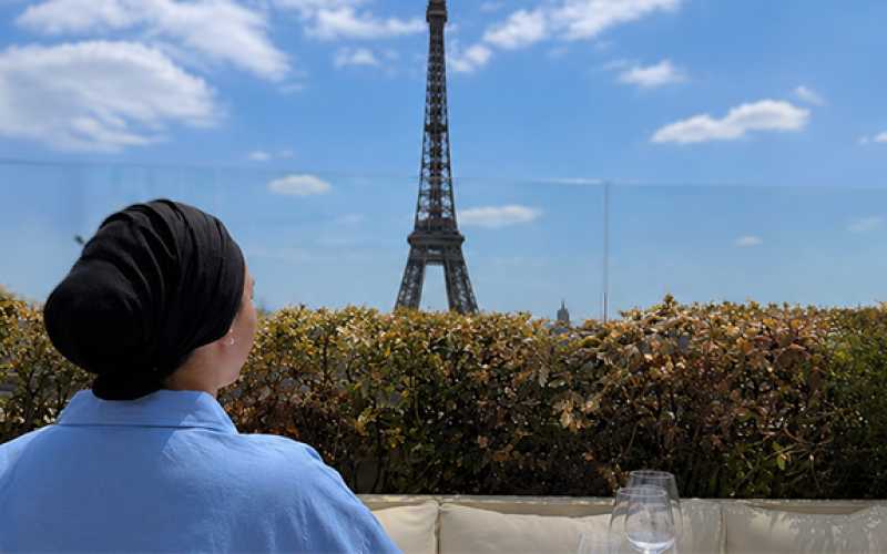 Saria de dos habillée d'une blouse bleur regardant la tour Eiffel