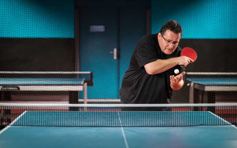 Christophe faisant un service au tennis de table