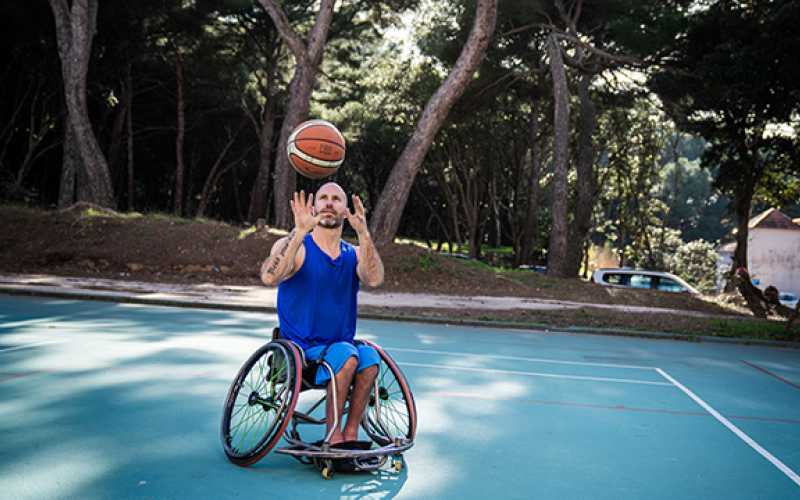 Jérôme, en fauteuil roulant et lançant un ballon de basket