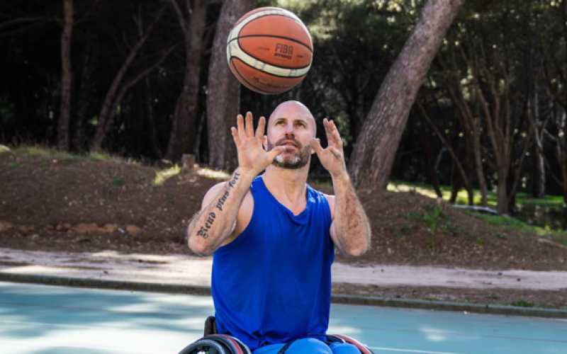 Jérôme Durand avec un maillot bleu attrapant un ballon de basket