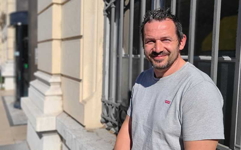 Homme brun avec tee-shirt gris clair et souriant