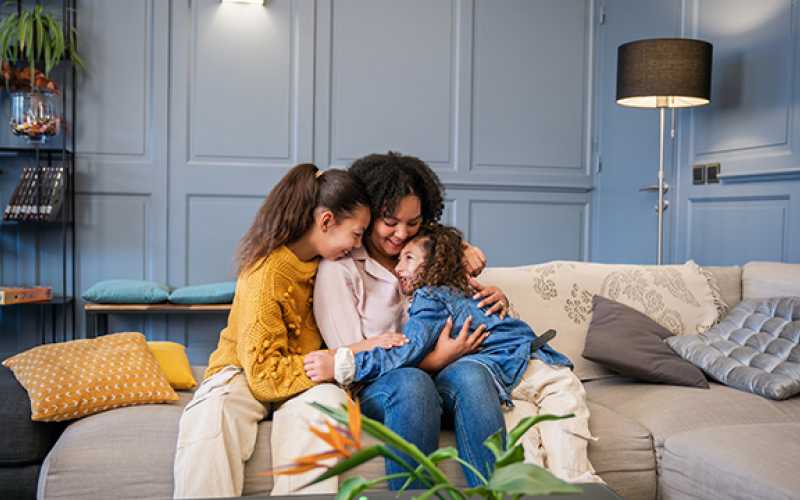 Moment de tendresse entre Anne-Sophie et ses filles sur un canapé