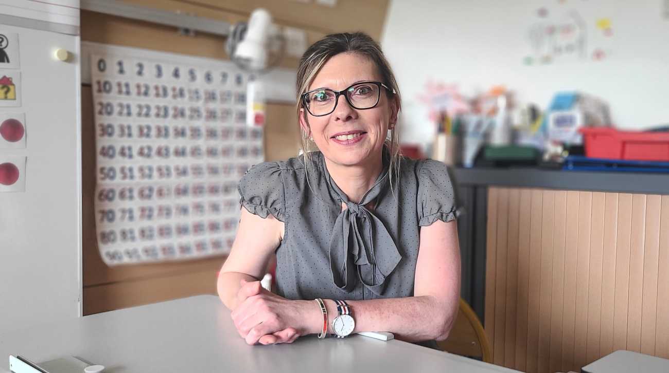 Femme souriante portant des lunettes bras sur une table de classe