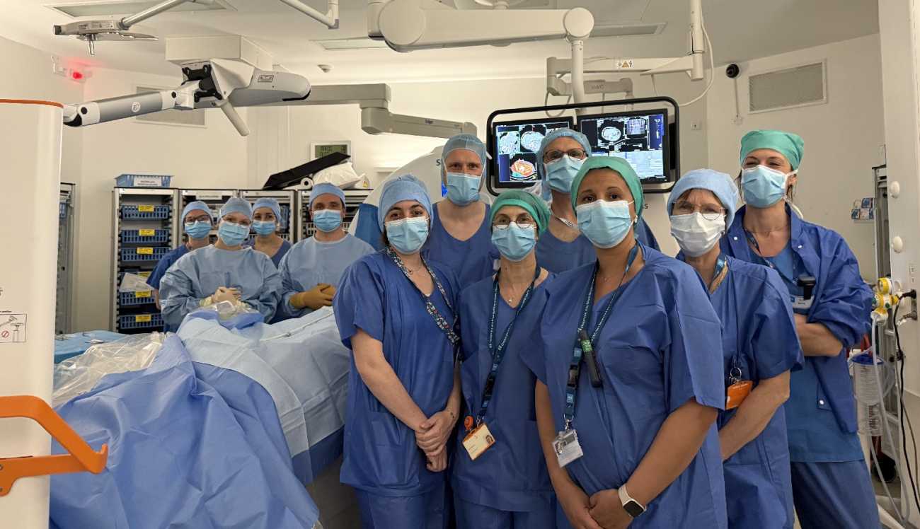 une équipe de professionnels de santé, en blouses bleues, pose dans une salle d'opération