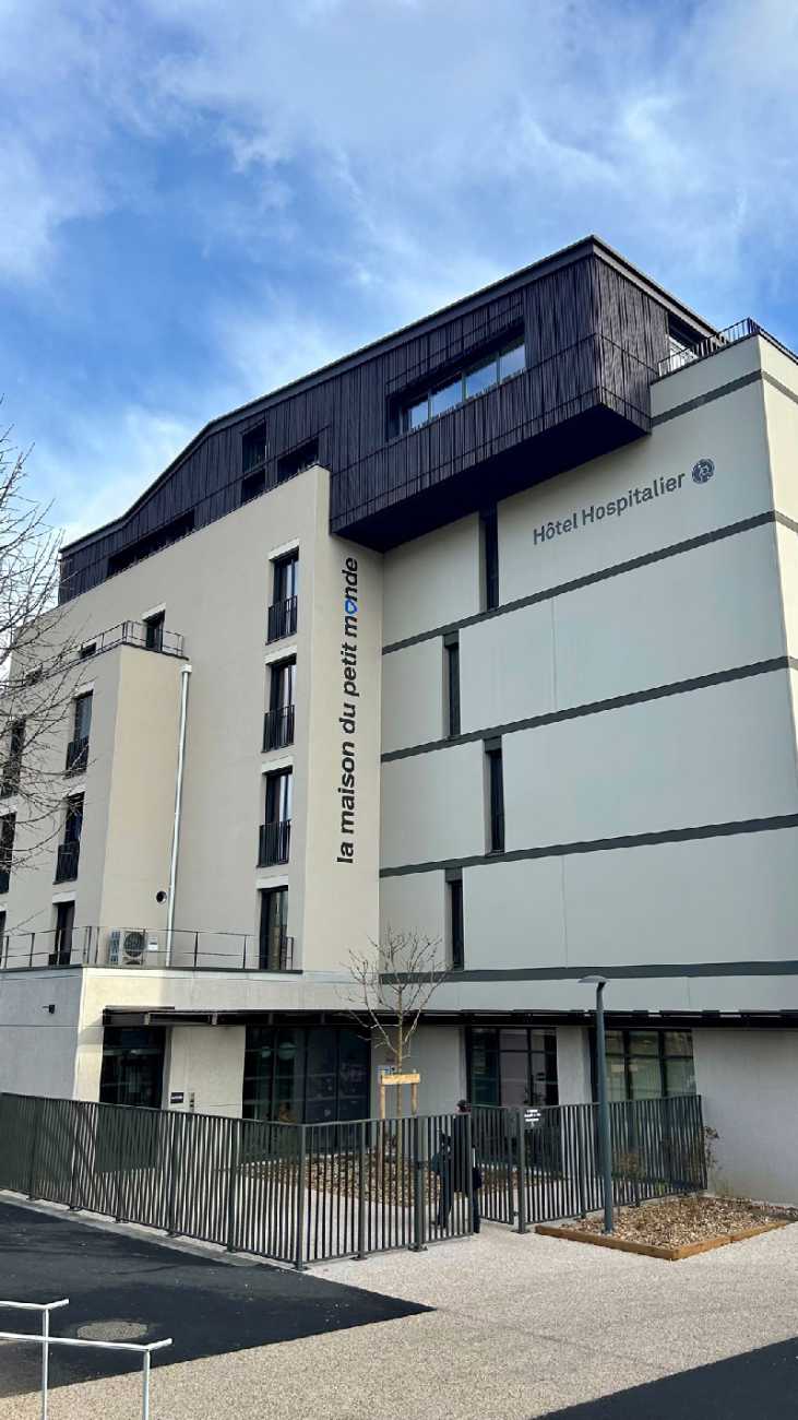 vue extérieur de la facade beige de la maison du petit monde, hotel hospitalier de la Croix Rousse à Lyon. le ciel est bleu.