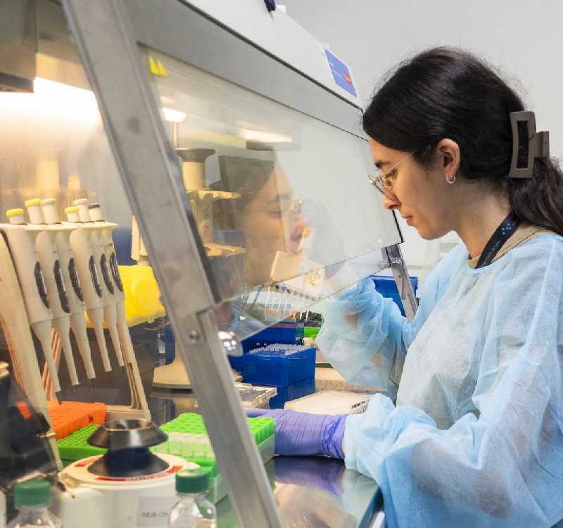 Une technicienne de laboratoire prépare des PCR, elle est en blouse bleue, avec des gants bleus