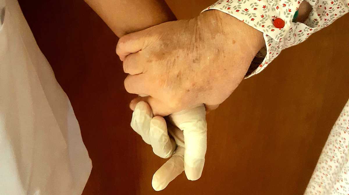 Aide-soignante tenant la main d'une patiente