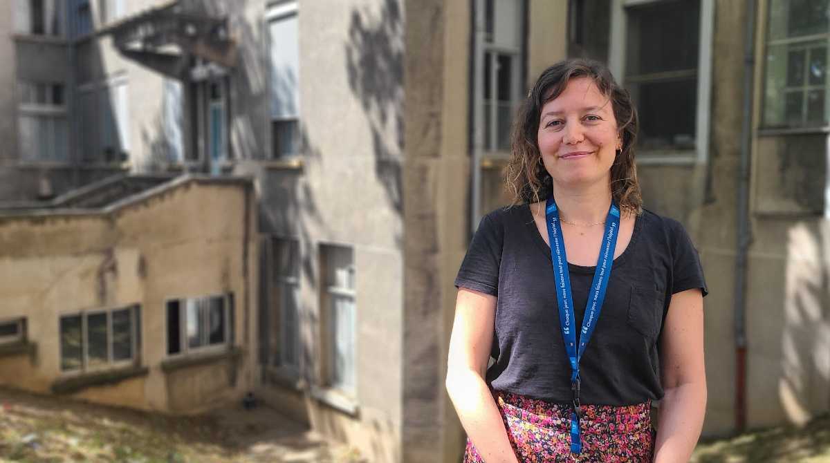 Femme brune souriante se tenant debout avec un t-shirt noir et un bas fleuri.  