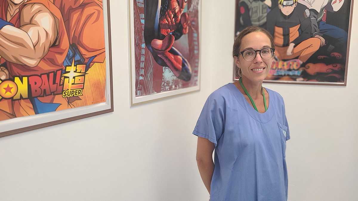 Chirurgienne en blouse bleue portant des lunettes devant des affiches accrochées au mur
