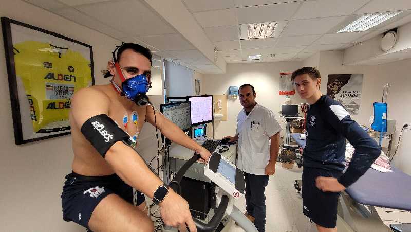 Un sportif fait un bilan dans un service de médecine du sport de l’hôpital de la Croix-Rousse. il réalise un test d’effort. En arrière plan, un médecin et un autre sportif le regarde.