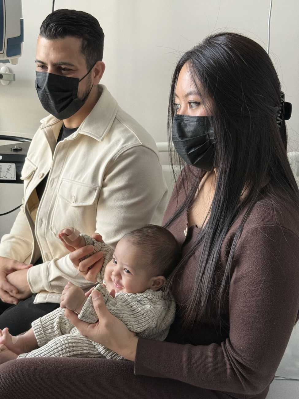 Issa, nouvea-né et ses parents assis avec des masques chirurgicaux noirs