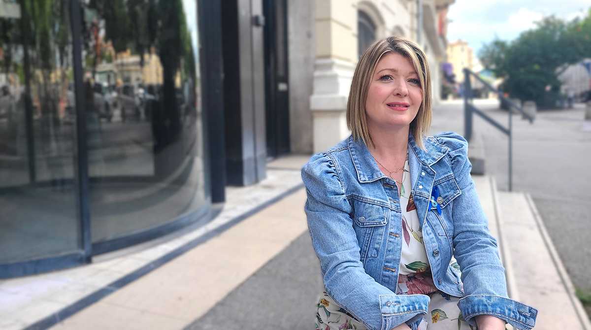Femme blonde cheveux au carré assise avec veste en jean bleue