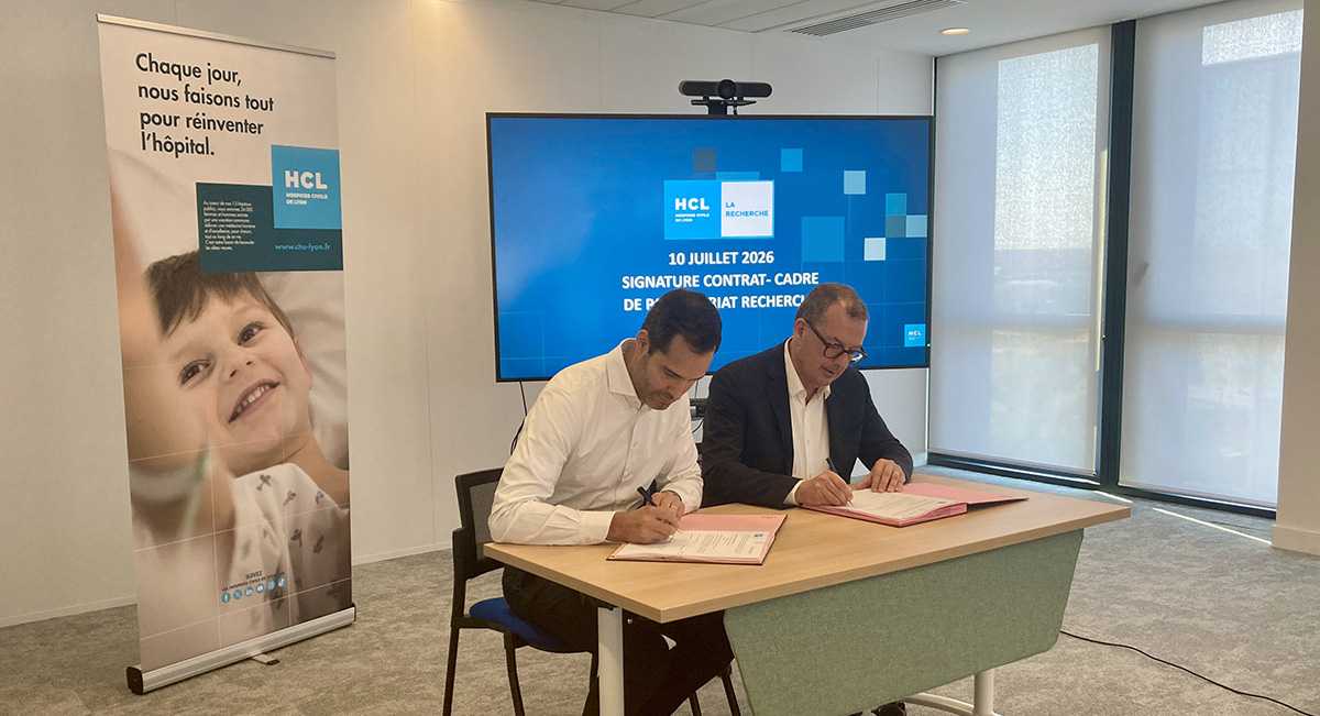 Deux hommes assis en train de signer des documents sur une table