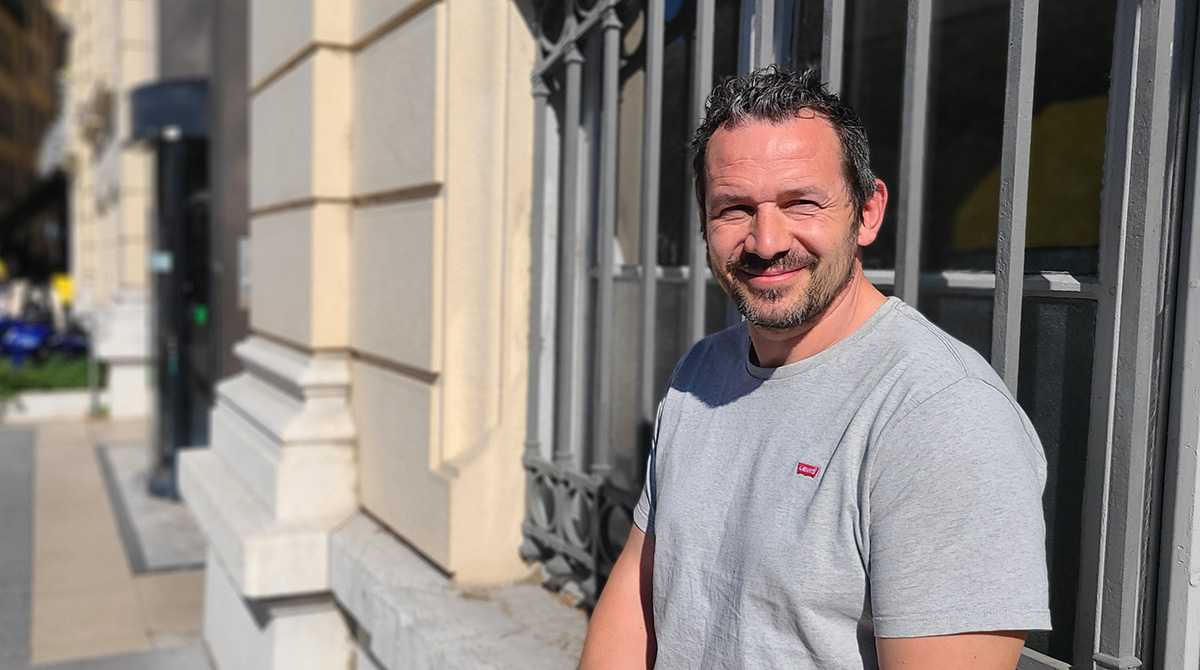 Homme brun souriant avec barbe et t-shirt gris clair
