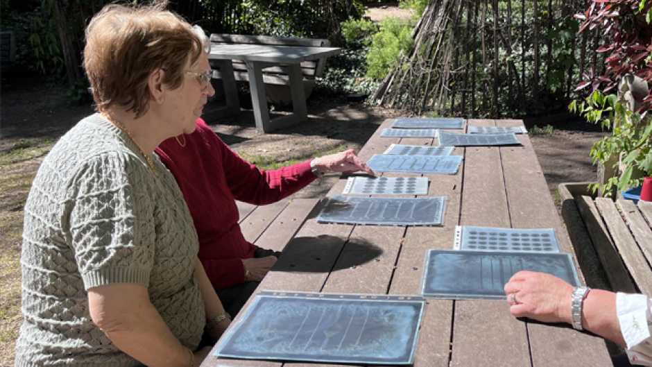 Personnes âgées assises sur un banc en bois à l'extérieur avec sur la table des exemples de cyanotype