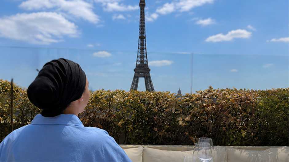 Saria de dos habillée d'une blouse bleur regardant la tour Eiffel